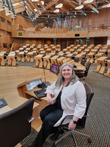 Roz McCall MSP sitting at a desk in the Chamber in the Scottish Parliament